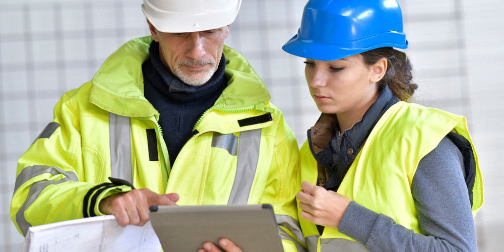 Construction instructor supporting an apprentice on a UK construction site during practical training